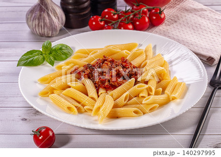 Penne pasta with meat sauce and fresh basil on white plate Penne pasta with meat sauce and fresh basil on white plate 140297995