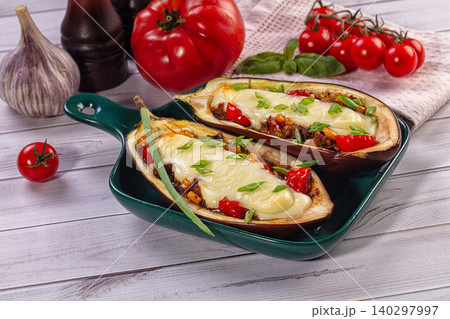 Stuffed Eggplant Halves with Cheese and Vegetables in Green Dish on Wooden Table Stuffed Eggplant Halves with Cheese and Vegetables in Green Dish on Wooden Table 140297997