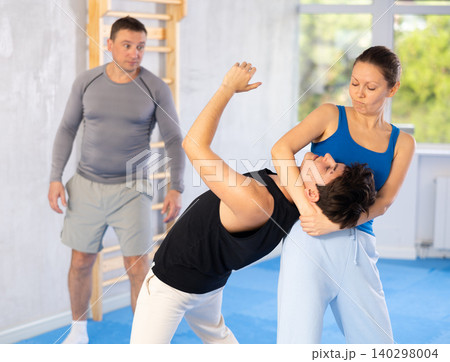 Guy and woman train to perform defense of strangling opponent, while learning self-defense Guy and woman train to perform defense of strangling opponent, while learning self-defense 140298004