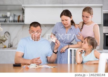 Dissatisfied husband and father give out pocket money to wife and children in kitchen 140298144