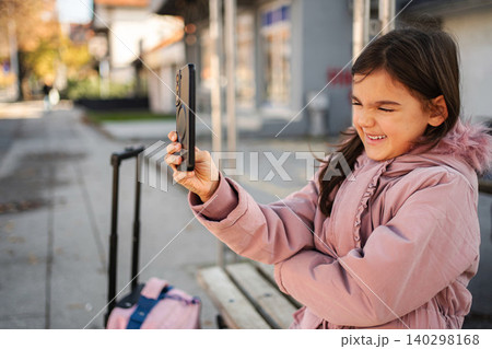 Little girl using smartphone for video call outdoors 140298168