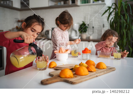 Sisters making fresh orange juice in kitchen 140298212