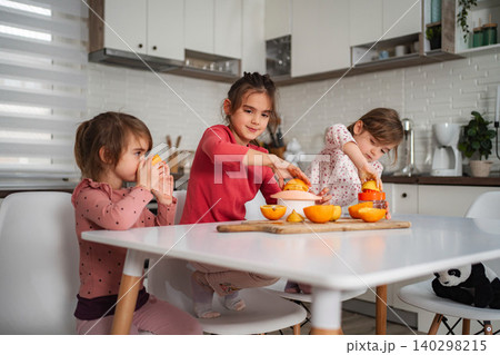 Girls making fresh orange juice in kitchen at home Girls making fresh orange juice in kitchen at home 140298215