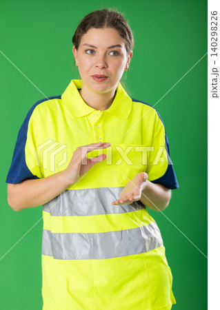 Young woman in polo shirt with reflective stripes is talking to someone against green background 140298226