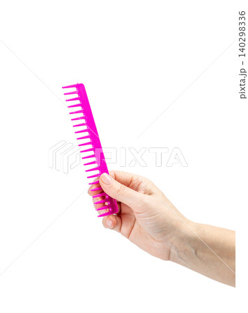 Red comb in the woman's hand on the white background. Red comb in the woman's hand on the white background. 140298336