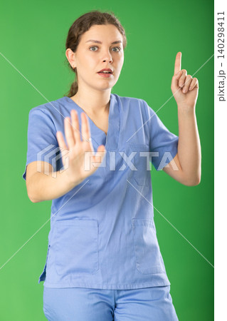 Serious young female medic in blue uniform warning about prohibitions Serious young female medic in blue uniform warning about prohibitions 140298411