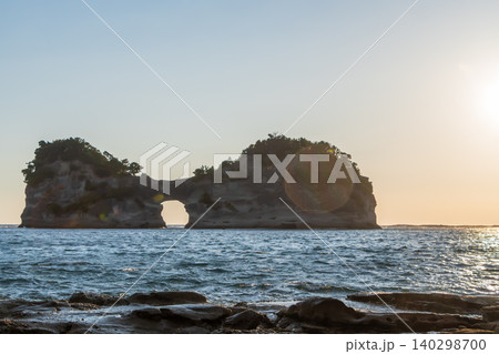 夕暮れ時の海に浮かぶ円月島と美しい波打ち際 140298700