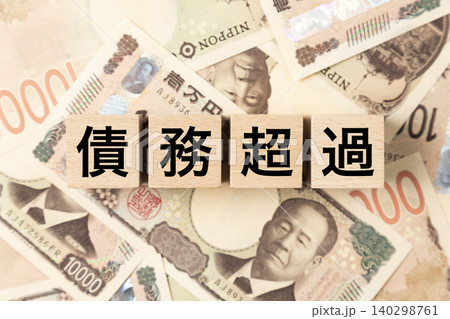 「債務超過」と書かれたブロックとたくさんの一万円札 「債務超過」と書かれたブロックとたくさんの一万円札 140298761