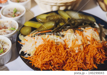 Traditional Russian cuisine dishes on a New Year table, dressed herring salad, kholodets brawn, russian snacks, olivier salad and homemade pickles on catering table banquet, party event celebration 140299043