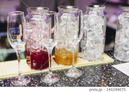Barman mixing and pouring drinks and beverages, beautiful row line of different coloured lemonades in a jar, liquor alcohol cocktails on a party in bar, catering banquet on event, mocktails in a jug Barman mixing and pouring drinks and beverages, beautiful row line of different coloured lemonades in a jar, liquor alcohol cocktails on a party in bar, catering banquet on event, mocktails in a jug 140299075