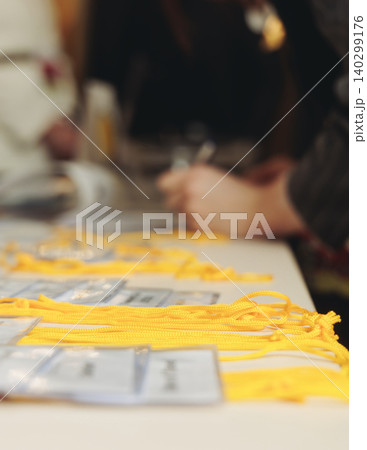 Process of checking in on conference congress forum event, registration desk table, visitors and attendees receiving lanyard with name badge and entry wristband bracelet and register electronic ticket Process of checking in on conference congress forum event, registration desk table, visitors and attendees receiving lanyard with name badge and entry wristband bracelet and register electronic ticket 140299176