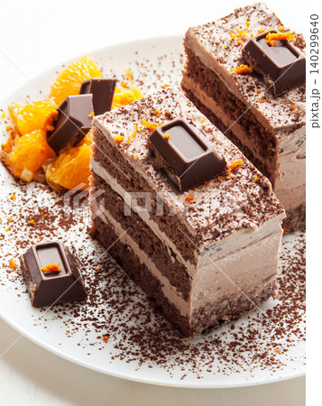 Traditional chocolate cocoa butter condensed milk cream cake with candies, oranges served on plate. Traditional chocolate cocoa butter condensed milk cream cake with candies, oranges served on plate. 140299640