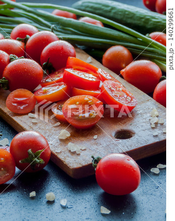 Red cherry tomatoes with herbs and leek sprinkled with sea salt on wooden board on table Red cherry tomatoes with herbs and leek sprinkled with sea salt on wooden board on table 140299661