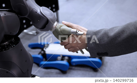 AI Robot shaking hands with man. Close up of human shaking hand with robotic arm. Symbolizing collaborate between people and artificial intelligence or AI. Automation robot innovate future technology 140299716