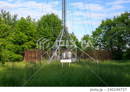Lattice telecommunication mast for mobile internet signal and TV broadcast, tall cellular connection tower in green field 140299737