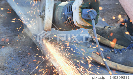 Worker cutting metal profile with an angle grinder sparking and creating heat 140299851