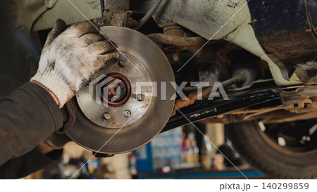 Mechanic replacing brake disc of a car using a wrench Mechanic replacing brake disc of a car using a wrench 140299859