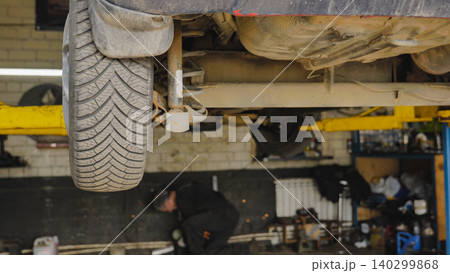 Car lifted on a hydraulic lift during maintenance in a garage Car lifted on a hydraulic lift during maintenance in a garage 140299868