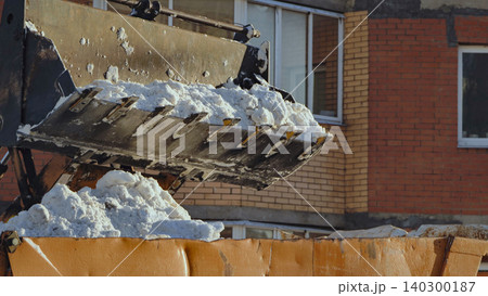 Excavator bucket loading white snow into dump truck, city street snow removal Excavator bucket loading white snow into dump truck, city street snow removal 140300187