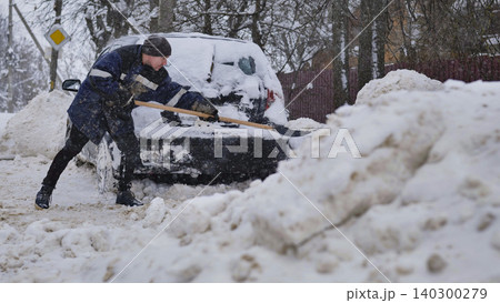Man shoveling heavy snow from buried car after blizzard, winter clean-up Man shoveling heavy snow from buried car after blizzard, winter clean-up 140300279