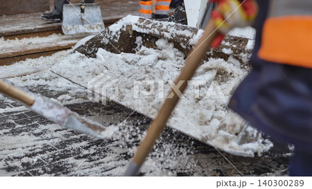 Workers manually shoveling snow and ice on a harsh winter day for city cleanup Workers manually shoveling snow and ice on a harsh winter day for city cleanup 140300289