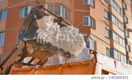 Snow loader filling dump truck with snow during urban winter cleanup 140300301