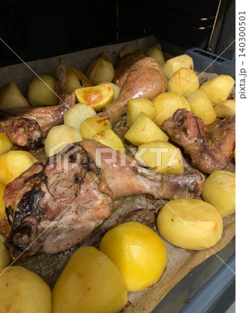A whole chicken is placed in the oven with potatoes. The dish is being cooked for dinner. The kitchen is warm and smells delicious as the food bakes A whole chicken is placed in the oven with potatoes. The dish is being cooked for dinner. The kitchen is warm and smells delicious as the food bakes 140300501