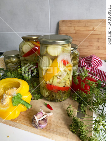 People prepare jars of cucumbers and peppers for canning in the kitchen. The process involves boiling jars to seal them for winter use. Fresh ingredients are used People prepare jars of cucumbers and peppers for canning in the kitchen. The process involves boiling jars to seal them for winter use. Fresh ingredients are used 140300511