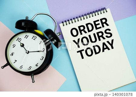 Order Yours Today text written on notepad with alarm clock flat lay on multicolor pastel background 140301078