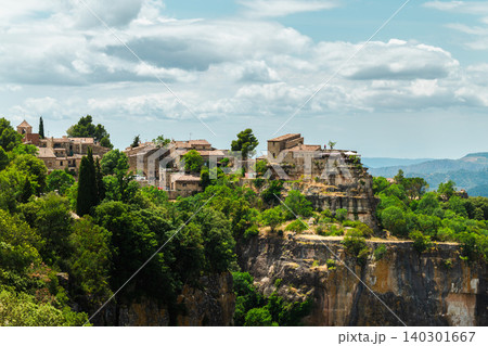 Stone village of Siurana perched on dramatic sandstone cliffs in Catalonia Spain overlooking rugged mountain landscape under summer clouds Stone village of Siurana perched on dramatic sandstone cliffs in Catalonia Spain overlooking rugged mountain landscape under summer clouds 140301667