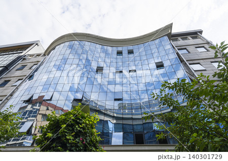 Modern buildings with reflective glass facades capture the sky and surrounding architecture in Skopje, North Macedonia Modern buildings with reflective glass facades capture the sky and surrounding architecture in Skopje, North Macedonia 140301729