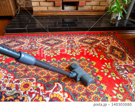 side view of vacuum cleaner cleans red carpet 140303080