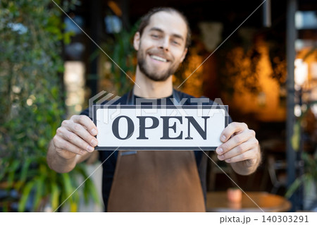 Close up of smiling barista showing open sign to camera Close up of smiling barista showing open sign to camera 140303291