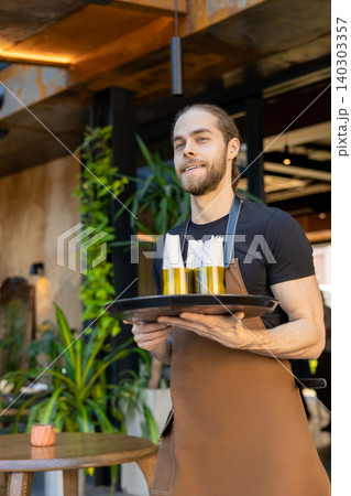 Young waiter serving orders on terrace Young waiter serving orders on terrace 140303357