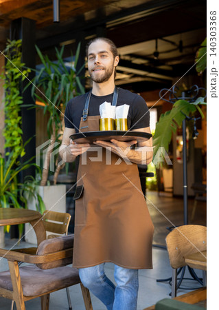 Cheerful server holding tray in cafe Cheerful server holding tray in cafe 140303368