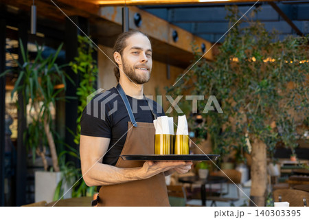 Male restaurant employee holding tray with napkins 140303395