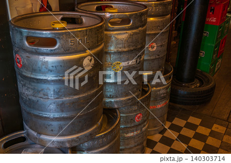 Amsterdam, Netherlands, 22.04.2026 - Metal beer kegs stacked inside a pub backdoor or storage room, 50l stainless steel barrels with brewery crates on background, traditional dutch bar interior 140303714
