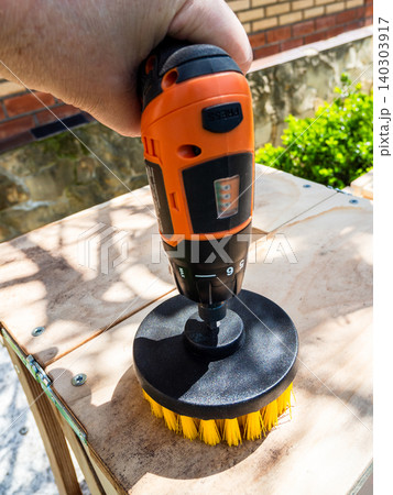 man cleans surface of bench from dust using brush 140303917