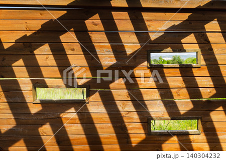 Abstract geometric shadow pattern inside wooden birdwatching hide, featuring observation windows and sunlight casting dramatic lines Abstract geometric shadow pattern inside wooden birdwatching hide, featuring observation windows and sunlight casting dramatic lines 140304232
