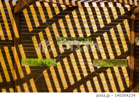 Wooden birdwatching hide with geometric shadows and observation windows in Les Madrigueres wetland reserve, Catalonia, Spain Wooden birdwatching hide with geometric shadows and observation windows in Les Madrigueres wetland reserve, Catalonia, Spain 140304234