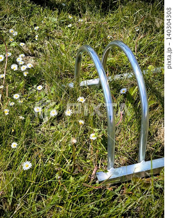 Bicycle parking in a green meadow with daisies on a sunny day. Bicycle parking in a green meadow with daisies on a sunny day. 140304308