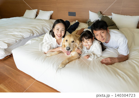 ベッドに寝転ぶ若い家族と犬 ベッドに寝転ぶ若い家族と犬 140304723