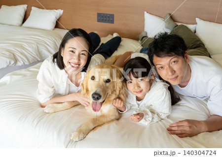 ベッドに寝転ぶ若い家族と犬 140304724