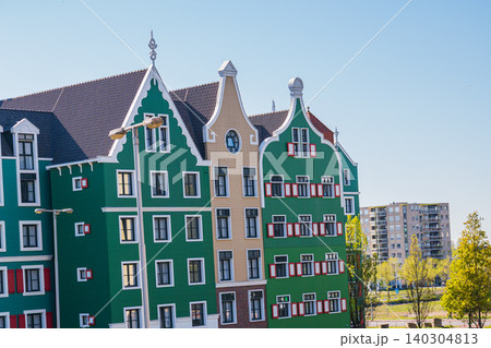 Modern green dutch building facade with traditional gables and red shutters in Zaandam, contemporary residential architecture project inspired by old holland houses, real estate concept 140304813