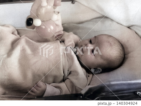 Vintage baby with rattle in a retro stroller scene Vintage baby with rattle in a retro stroller scene 140304924