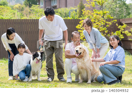 庭で犬と遊ぶ三世代家族 庭で犬と遊ぶ三世代家族 140304932
