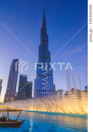 Dubai, United Arab Emirates - Jan 19 2024, vertical view of the Burj Khalifa Tower from below, with boat on foreground and dancing fountains, at evening with illumination, Dubai, UAE Dubai, United Arab Emirates - Jan 19 2024, vertical view of the Burj Khalifa Tower from below, with boat on foreground and dancing fountains, at evening with illumination, Dubai, UAE 140306400