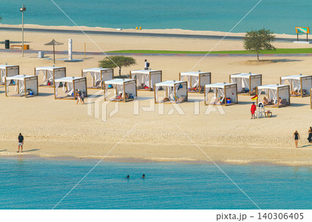 Sir Bani Yas island, United Arab Emirates - Jan 18 2024, aerial view of the beach with the azure sea, where people relax under umbrellas on sun loungers, at daytime, Sir Bani Yas island, UAE Sir Bani Yas island, United Arab Emirates - Jan 18 2024, aerial view of the beach with the azure sea, where people relax under umbrellas on sun loungers, at daytime, Sir Bani Yas island, UAE 140306405
