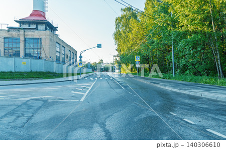 Empty urban road with industrial building and leafy trees at dawn 140306610