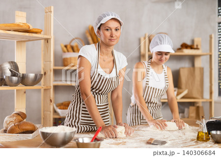Two bakery employees work together to prepare dough for baking baguettes and croissants Two bakery employees work together to prepare dough for baking baguettes and croissants 140306684